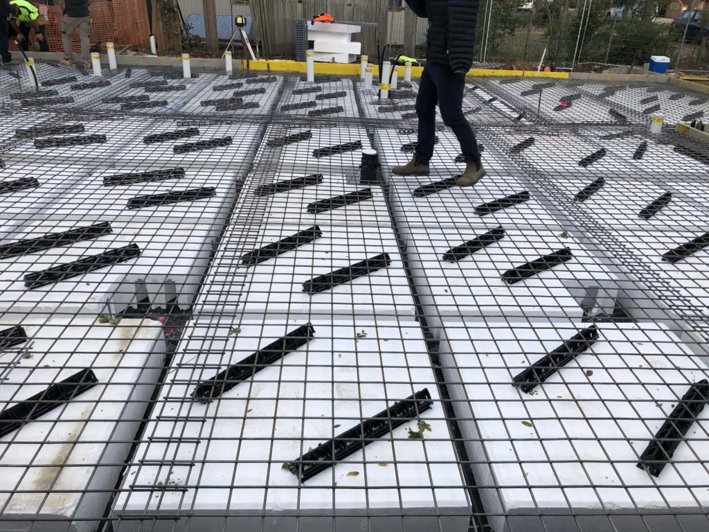 Photographie d'une dalle gaufrée en cours de construction. Les dalles gaufrées se situent près du niveau du sol et sont constituées d'une grille de coussins en mousse de polystyrène expansé qui forment les vides et créent un labyrinthe de poutres entre les deux. Le treillis supérieur est posé sur la partie supérieure des nacelles.