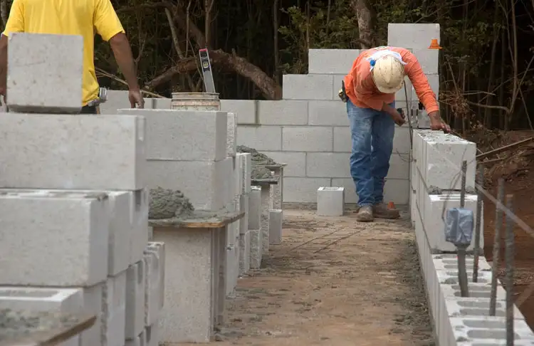 Photographie dun macon construisant un mur a laide de blocs de beton